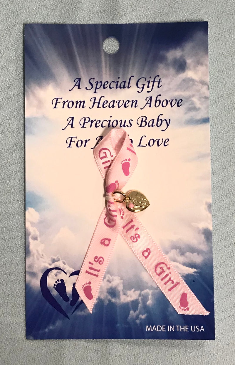 Pink ribbon says, "It's a Girl" with pink footprints. It has a gold colored Miraculous Medal inside a heart.